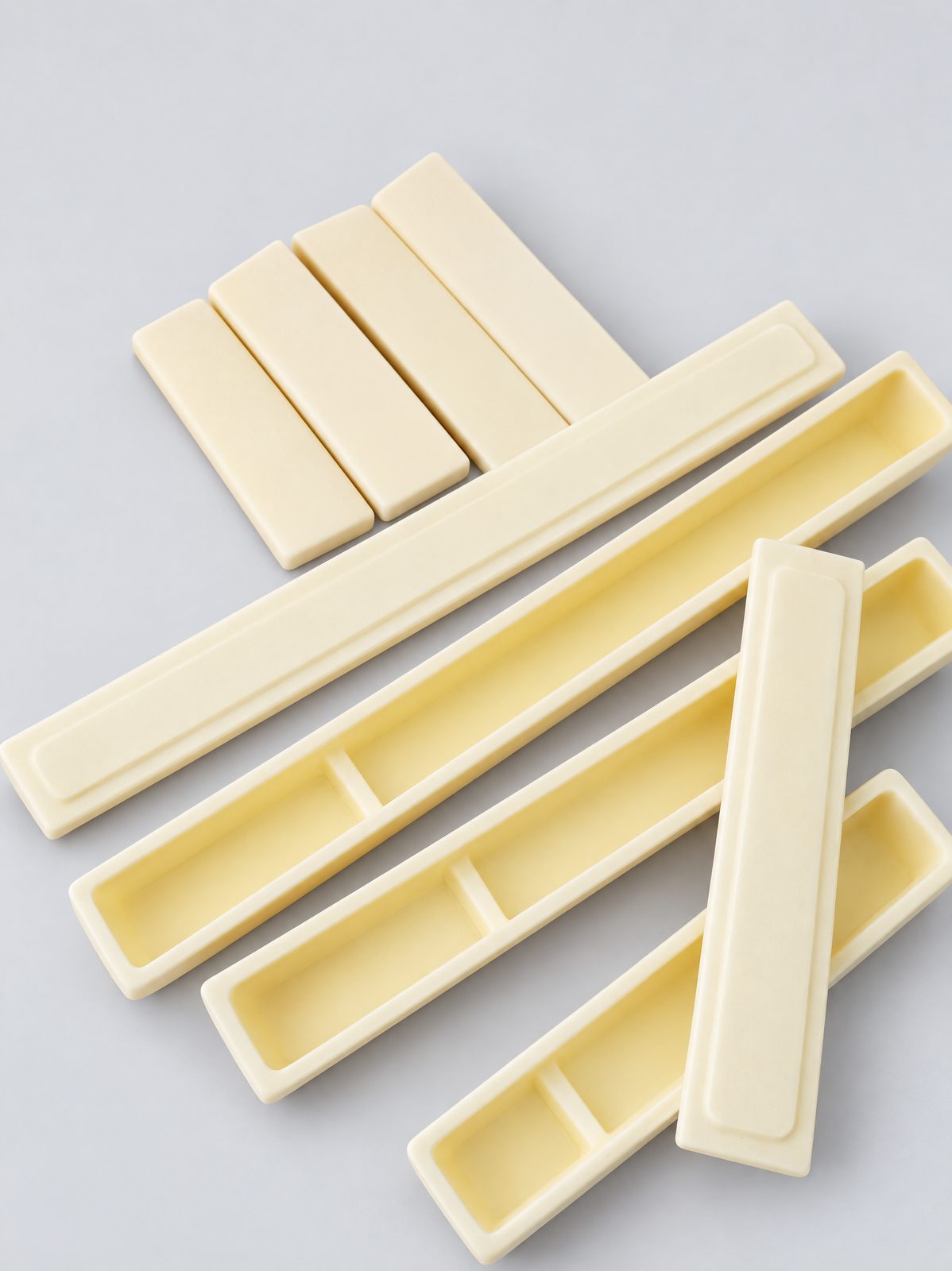Long narrow ceramic boats, each split into two compartments by a cross-wall, with flat plates and rectangular bars on wrapping paper.