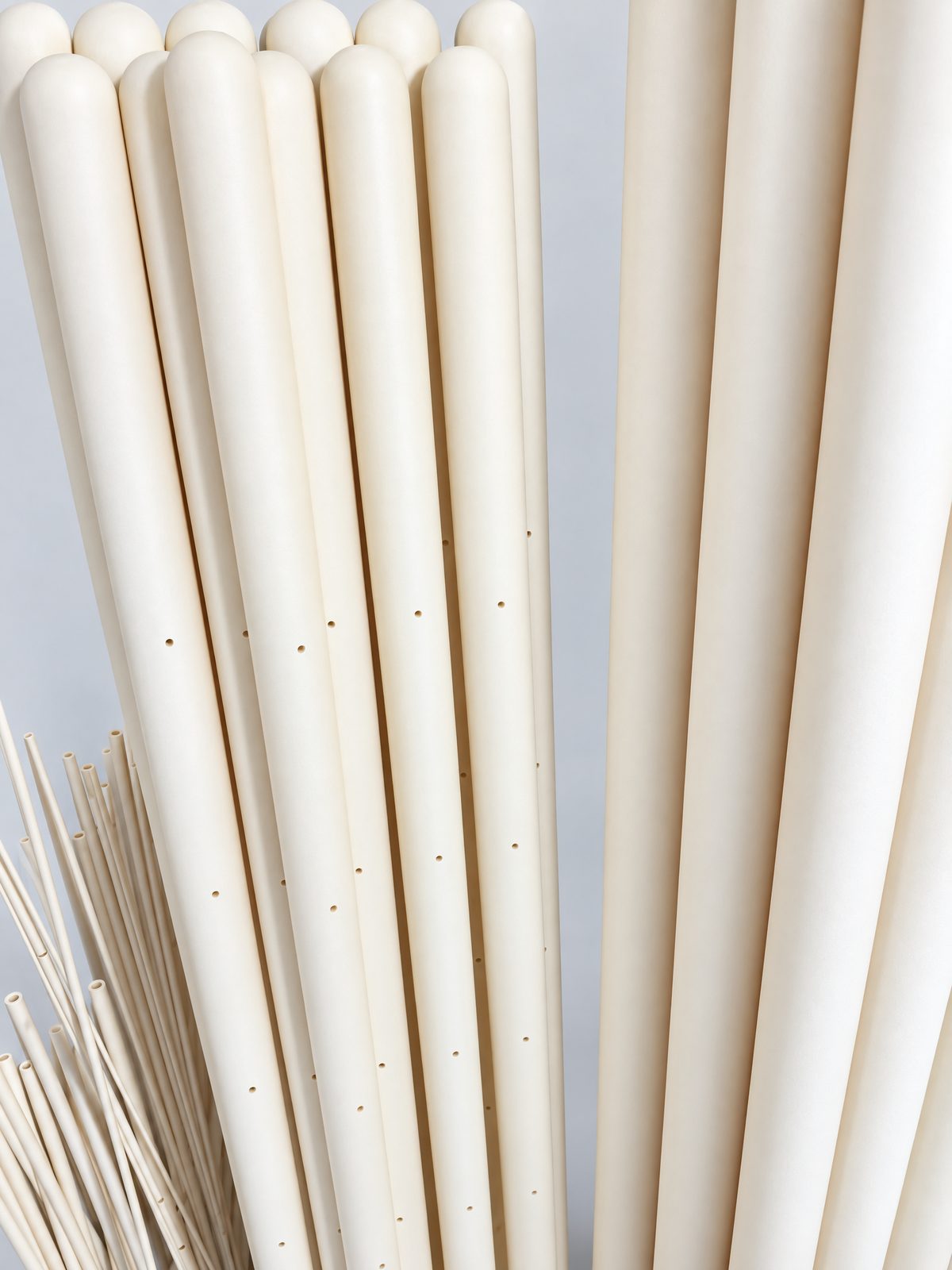 Long ivory tubes with rounded closed ends standing side by side, each with a single line of small holes along its length.